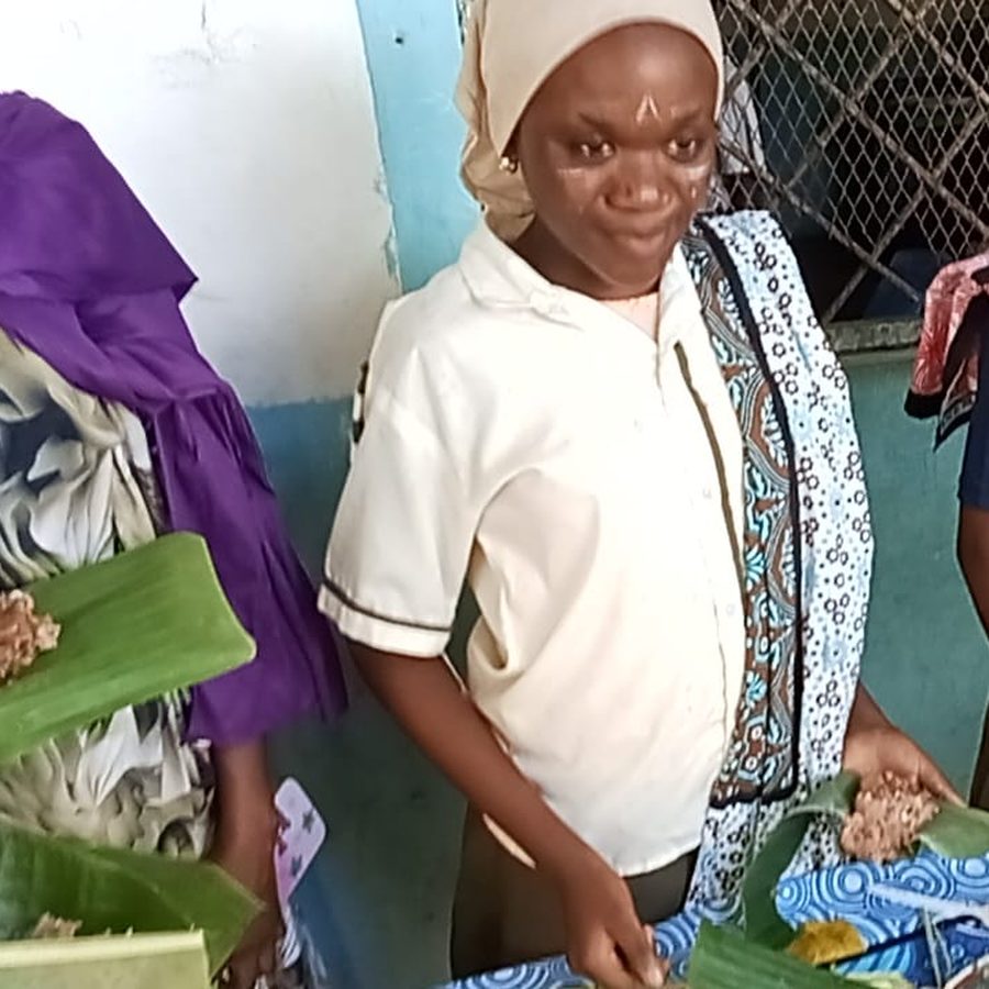 A learner in traditional dress serving food on Culture Day